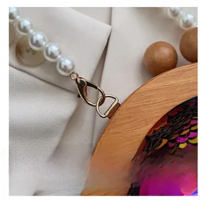 Detail of wooden frame with colorful sequins and white pearl strap on gold lobster clasp