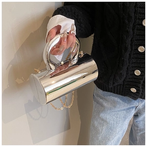 Detail of silver mirror acrylic cylinder bag featuring thick arc handle and chain strap