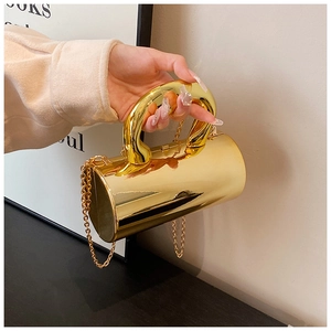 Polished gold cylinder box bag with metallic handle and chain strap detail