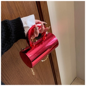 Detail of cylindrical fuchsia metallic evening bag with gold handle and chain strap