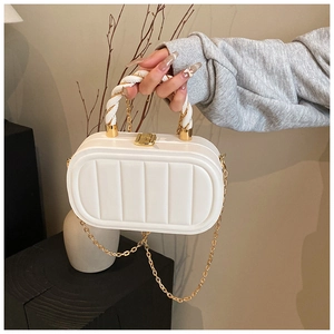 Detail of white quilted oval handbag featuring golden twist lock and chain strap