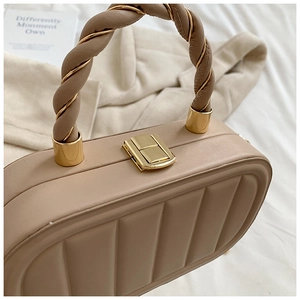 Détail du sac rigide beige en acrylique avec texture plissée et poignée torsadée