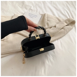Détails de l'intérieur du sac rigide noir avec poignée tressée et chaîne dorée