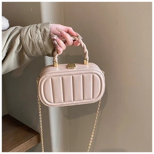 Détail du sac boîte beige matelassé avec fermoir doré et poignée torsadée élégante