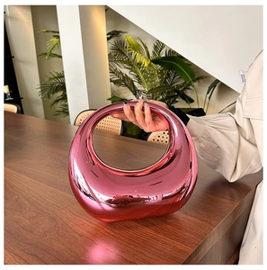 Detail view of the metallic pink acrylic circular handbag with a unique hollow cut-out handle