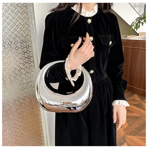 Mirror-finish silver crescent handbag held by model showing reflective metallic surface