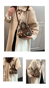 Detail of dark brown leather handbag featuring gold metal clasp and plush bear charm accessory