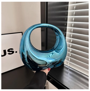 Detail of creative circular bright blue mirror acrylic handbag with sleek hollow handle
