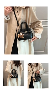 Detail of black leather Kelly bag with gold hardware and brown plush charm