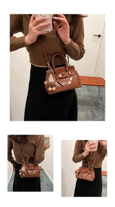 Brown lychee leather mini handbag with adjustable strap and plush monster charm detail