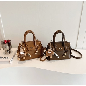 Detail of vintage leather Kelly bag with metal lock and cute plush pendant charm