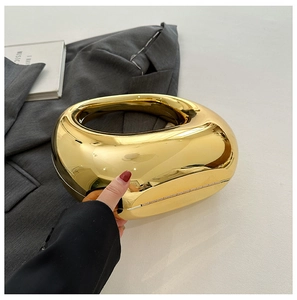 Close-up of golden doughnut-shaped evening clutch with mirrored finish and metal hinge