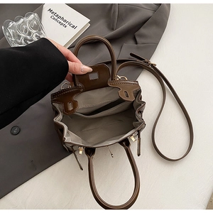Detail view of coffee leather bag interior with grey lining and gold hardware