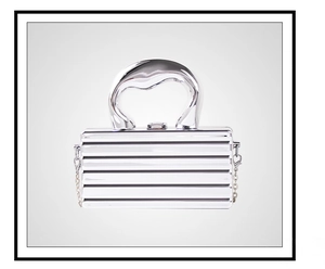 Close-up of a silver hard-shell mini bag with horizontal texture and a metal chain strap