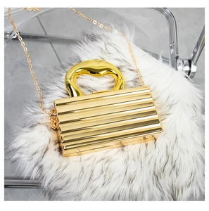 Detail of gold hard shell evening bag featuring vertical pleats and metallic handle