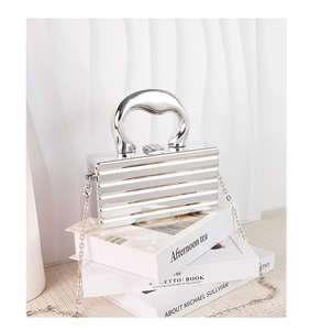 Detail of silver metallic textured clutch bag with geometric handle and chain strap