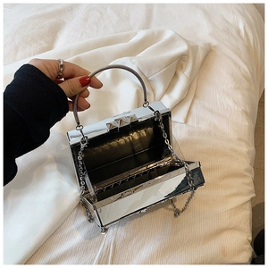 Detail of silver mirror box clutch showing metallic texture and internal storage space