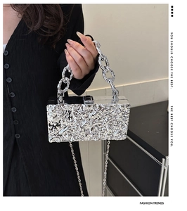 Detail of silver acrylic box bag with liquid metal texture and chunky chain handle