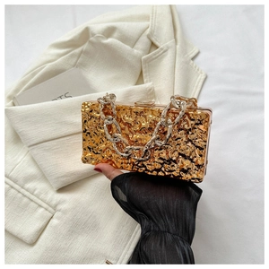 Detail of gold box clutch featuring hammered texture and chunky silver chain strap