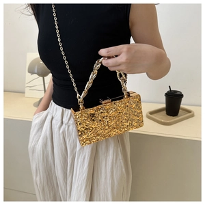 Close-up of gold acrylic evening bag with irregular molten texture and dual chain straps