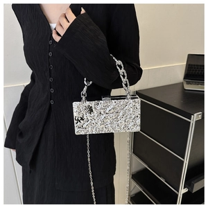 Detail of silver acrylic clutch bag featuring lava texture and metal chain straps