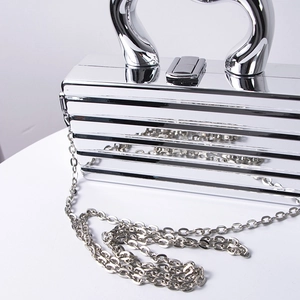 Silver metallic clutch with horizontal stripes, featuring a sleek ring handle and chain strap