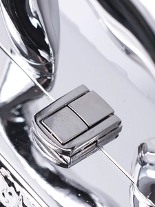 Detailed macro view of the silver metallic press-lock closure on an acrylic box bag