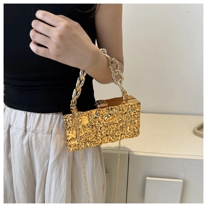 Detail of gold box clutch with lava texture and heavy chain strap for evening wear