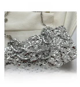 Close-up of silver acrylic box bag featuring unique molten lava texture and chain detail