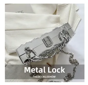 Close-up of a silver mirror acrylic clutch bag featuring a heavy hardware chain and clasp