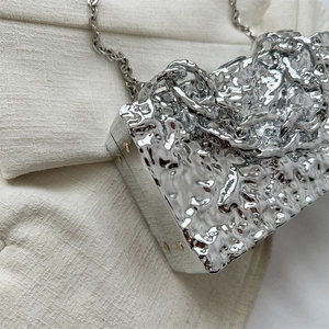 Close-up of silver liquid metal texture acrylic box bag with chunky chain detail