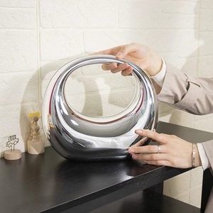 Silberne Acryl-Abendtasche in Halbmondform mit Kettengurt in der Hand gehalten