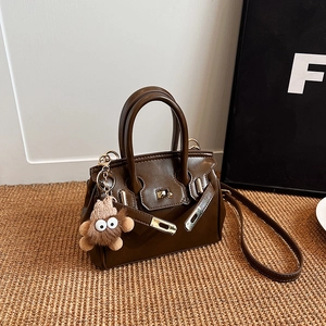 Classic dark brown leather handbag with gold lock and cute plush monster charm