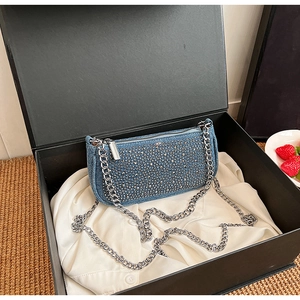 Close-up of sparkling denim rhinestone bag with silver chain in a premium gift box