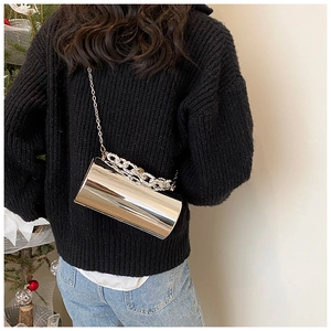 Silver mirror cylindrical crossbody bag with chain strap styled on a model outfit