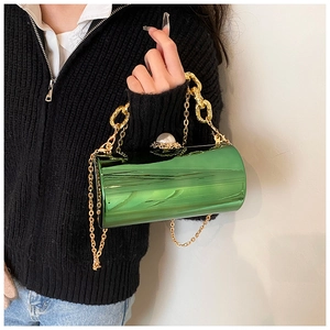 Detail of green acrylic cylinder bag featuring a large pearl clasp and gold chain strap