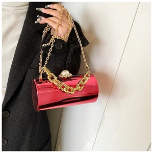 Detail of red cylindrical evening bag with pearl clasp and gold chunky chain decoration