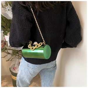 Detail of macaron green cylindrical acrylic bag with gold chains and pearl buckle