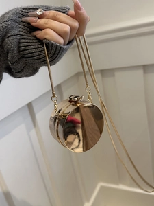 Dettaglio mini borsa tonda in acrilico con finitura a specchio oro e catena a serpente