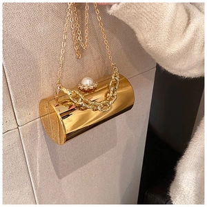 Detail of golden cylindrical evening bag with pearl clasp and chunky chain accent