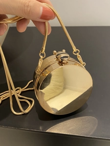 Dettaglio della borsa da sera tonda in metallo dorato con catena a serpente e chiusura