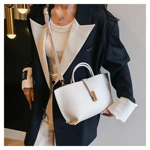 Detailed close-up of white lychee pattern leather tote bag with gold oval buckle and strap
