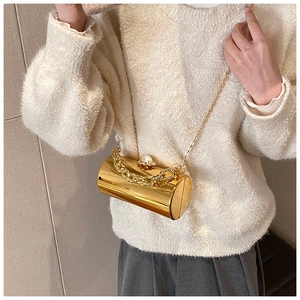 Detail of golden cylinder acrylic evening clutch with pearl clasp and chain strap