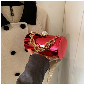 Detail of red cylindrical acrylic evening bag with pearl clasp and gold chain straps