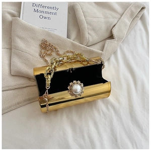 Detail of cylinder gold evening bag with pearl flower clasp and metal chain straps