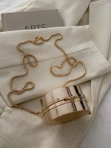 Dettaglio di borsa da sera rotonda oro specchiato con elegante tracolla a catenina