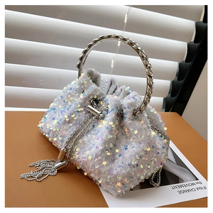 Close-up of white sequin bucket bag featuring metallic silver ring handle and chain tassel