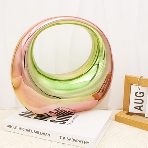 Iridescent circular ceramic vase with gradient metallic finish on art book decor