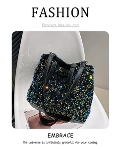 Sac fourre-tout à paillettes colorées avec bandoulières noires posé sur une chaise blanche