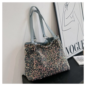 Détail d'un sac cabas à paillettes colorées avec lanières en cuir bleu et reflets métalliques
